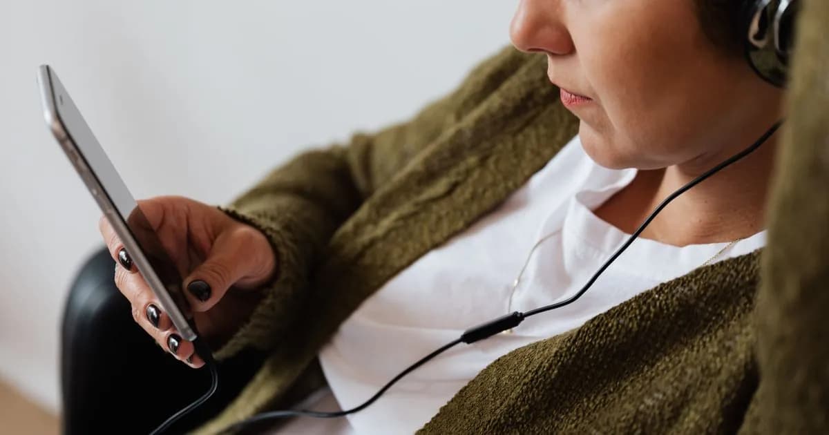 Person using a smartphone with headphones to listen to music, illustrating temp mail email privacy for Spotify sign-ups